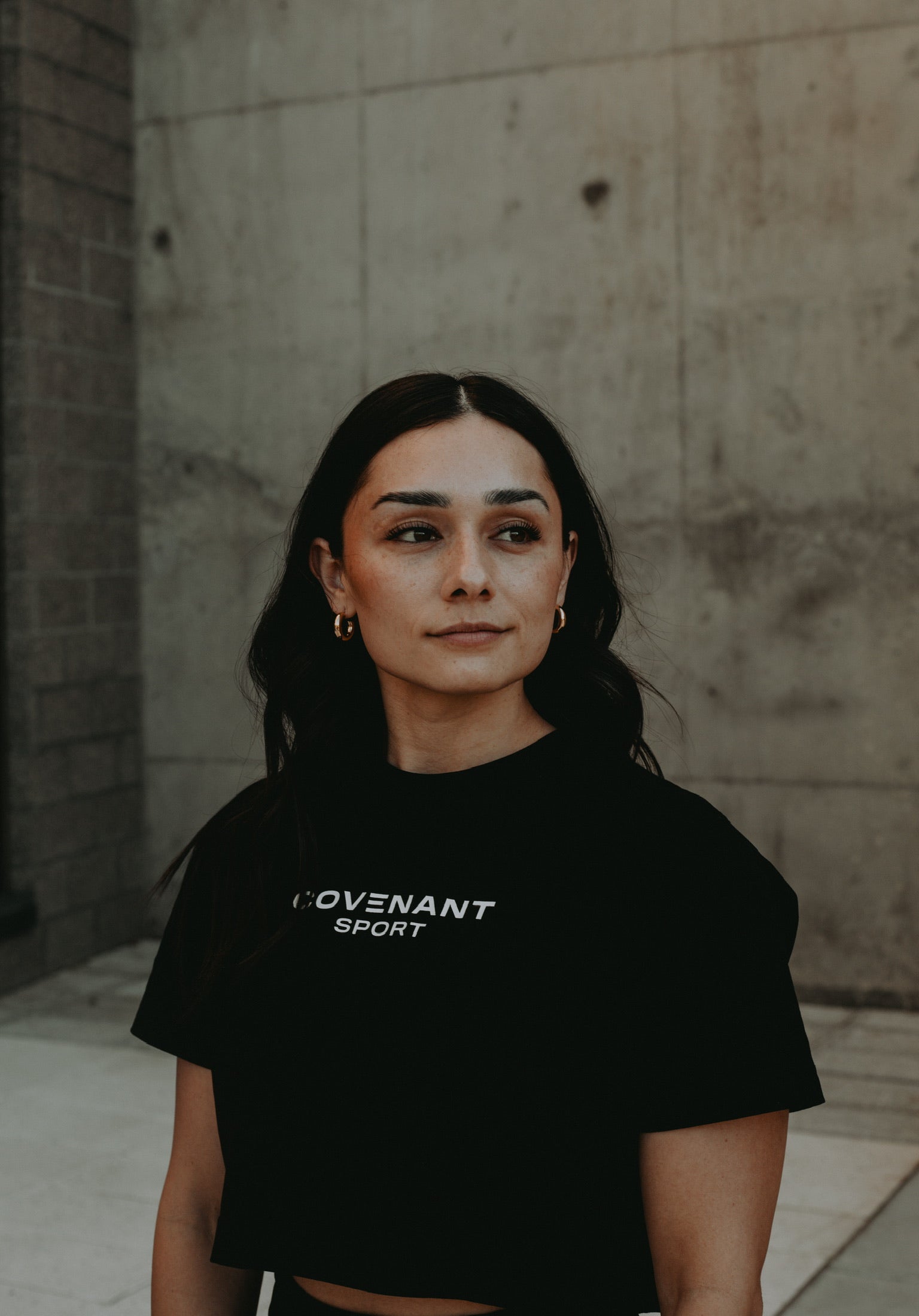 Female model in Covenant Collection Brushed Black Cropped Tee. 