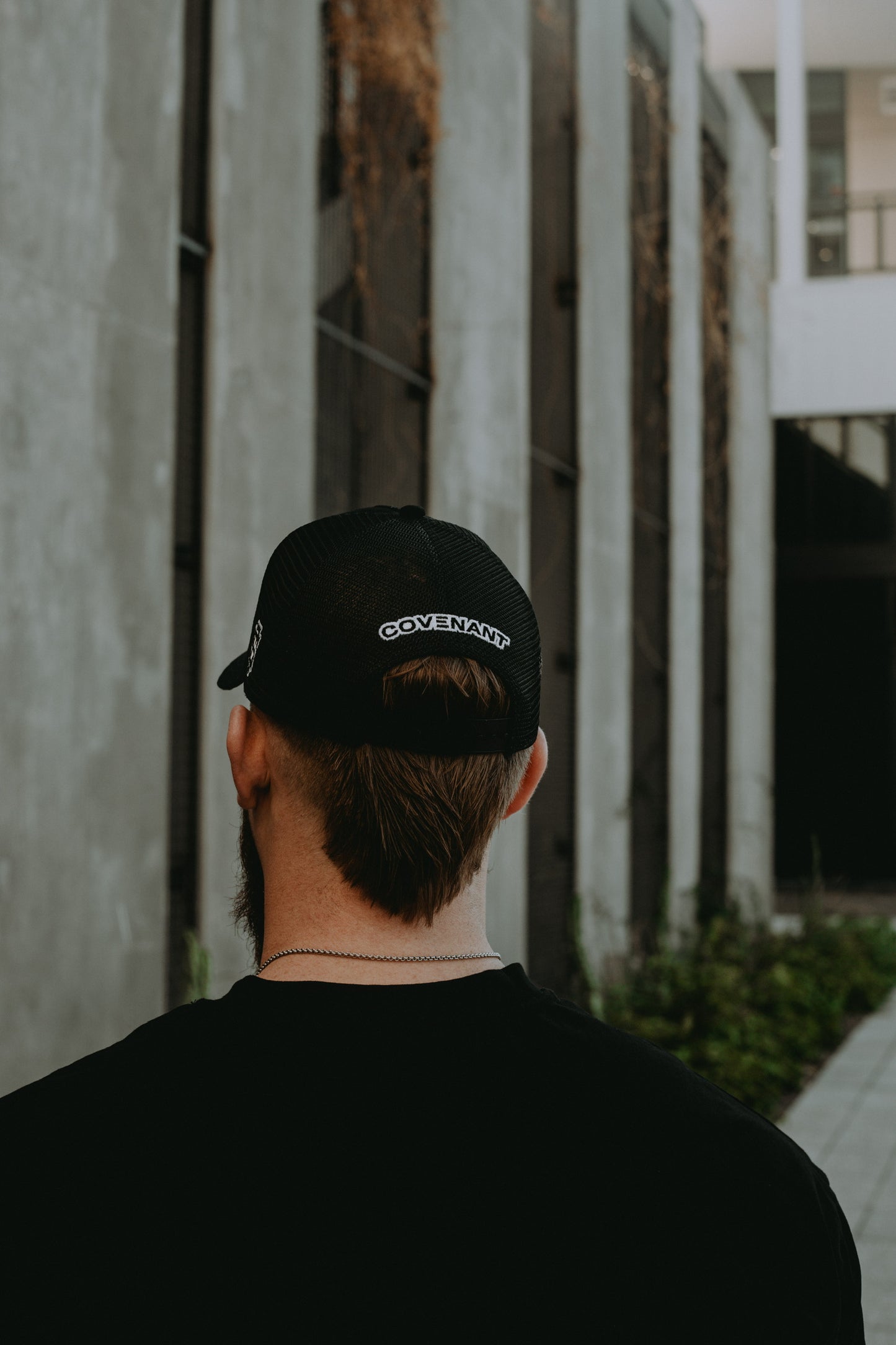 Male model showing the back of the Original Trucker Hat with the "Covenant" logo right above the snap back.