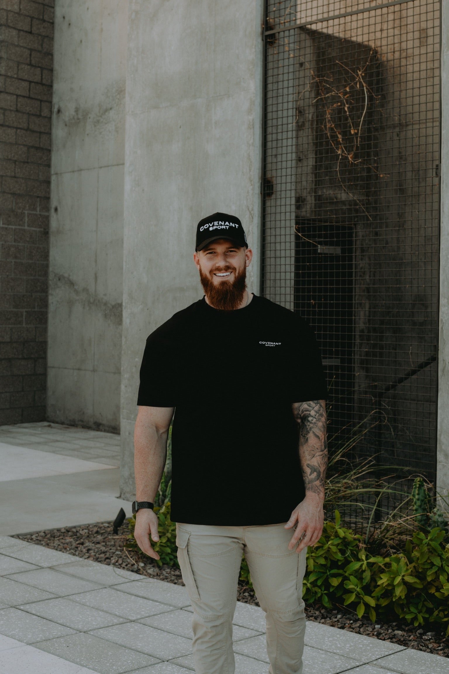 Model wearing the Brushed Black Minimalist Essentials Tee in a street wear fashion. The tee is oversized with longer and loose fitting sleeves, room in the shoulders chest and back, and a longer hem line.