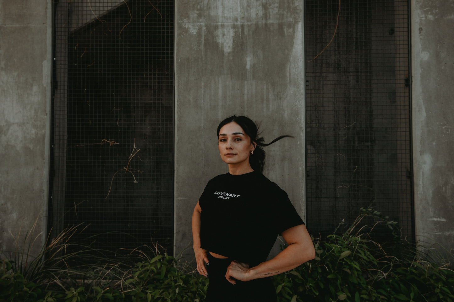 Model showing how the Brushed Black Minimalist Copped Tee fits. Falls just above the mid section, comfortable neckline, and loosely fitted sleeves. 