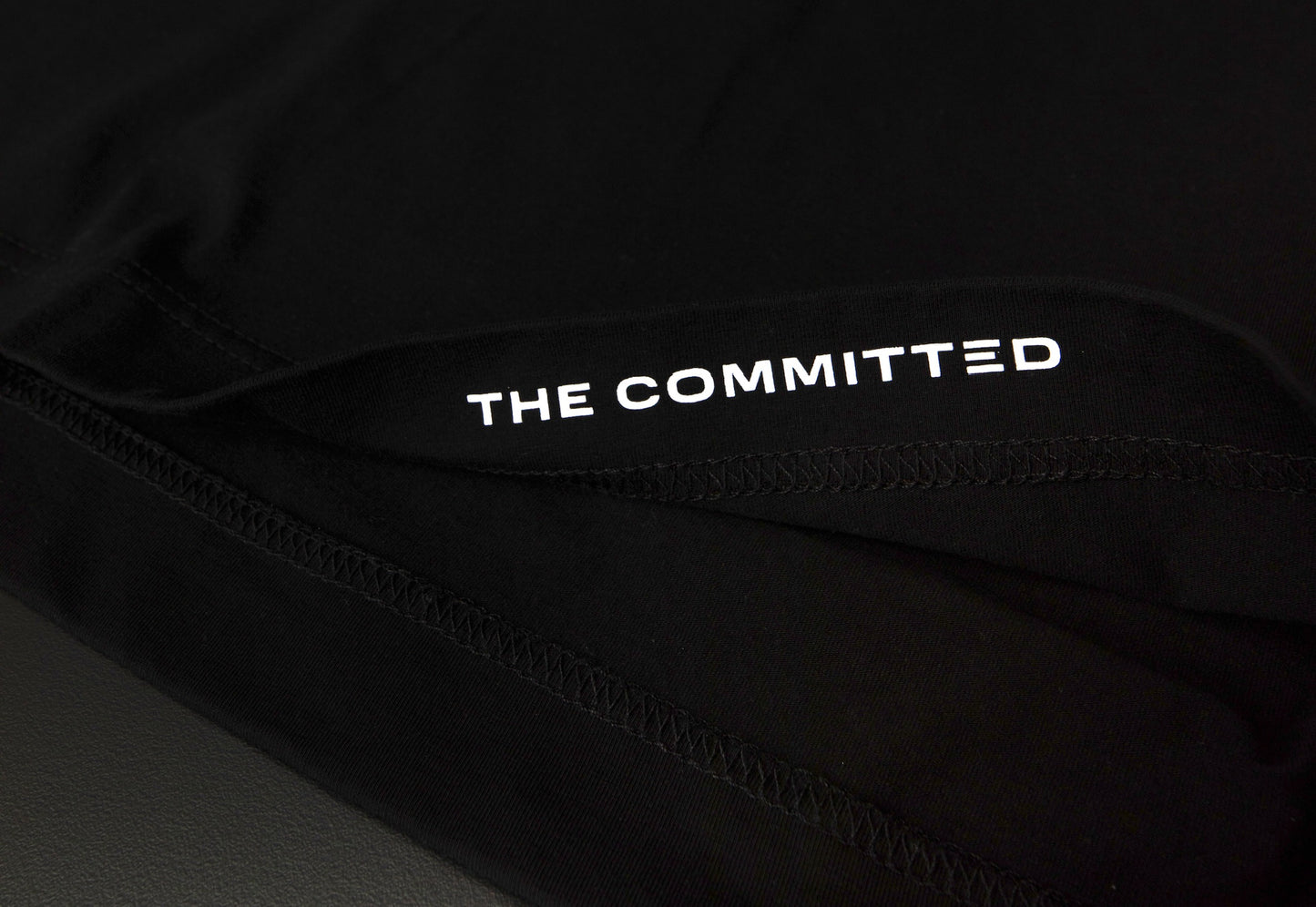 "The Committed" printed on the inside hem of each tee. 