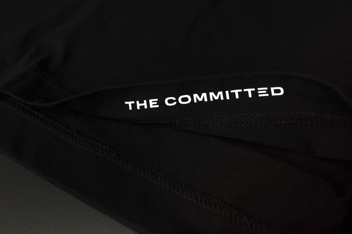 "The Committed" printed on the inside hem of each tee. 